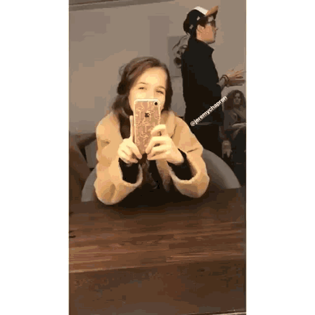 a young girl is taking a selfie in front of a mirror with her phone .