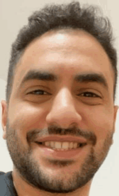 a close up of a man 's face with a beard and smiling .