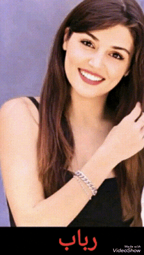 a woman wearing a black dress and a bracelet is smiling in a video show