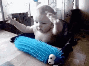 a baby is sitting in a high chair playing with a blue toy .