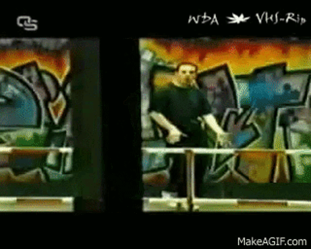 a man in a black shirt is standing in front of a graffiti wall .