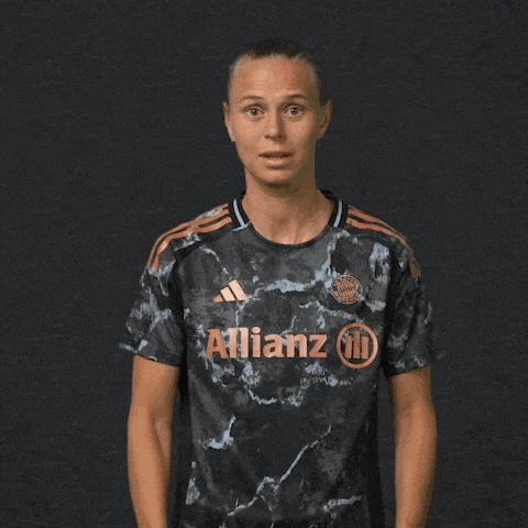 a woman wearing a black allianz shirt holds her hands out