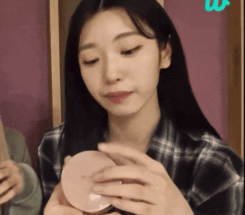 a woman in a plaid shirt is holding a pink container in her hands