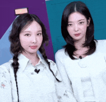 two women are standing next to each other in front of a purple door .