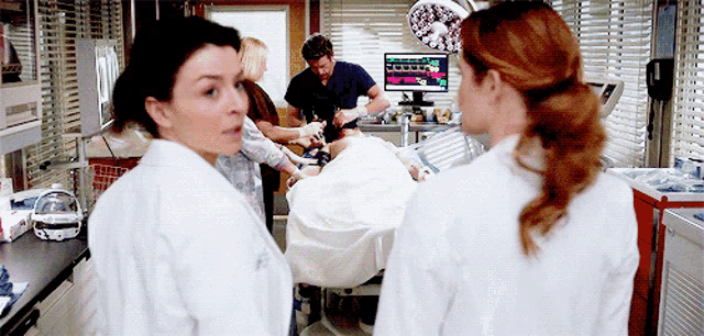 a group of doctors standing around a patient in a hospital room