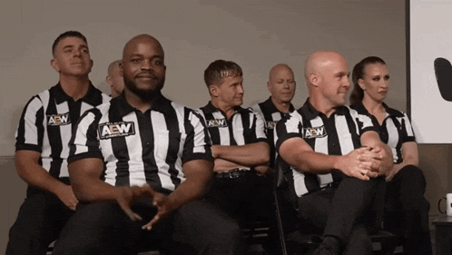 a group of men wearing aew shirts sit in chairs