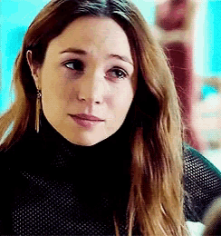 a close up of a woman 's face with a turtleneck and earrings