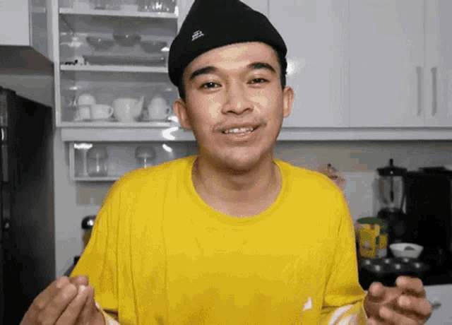 a man wearing a yellow shirt and a black hat with the word kangol