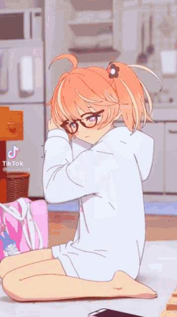 a girl with glasses is kneeling down on the floor in a kitchen .