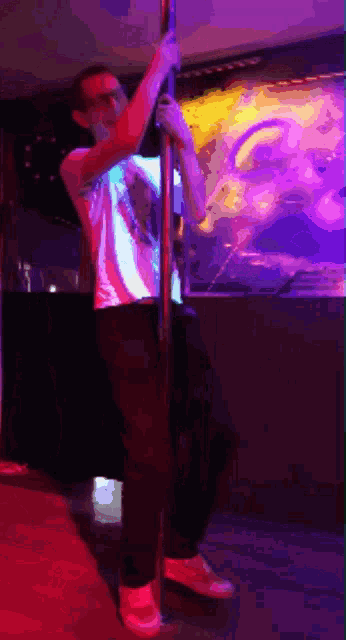 a man is standing on a pole in a dark room with purple lights