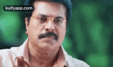 a close up of a man with glasses and a mustache .