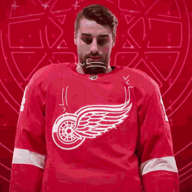 a man wearing a red jersey with a white winged wheel on it