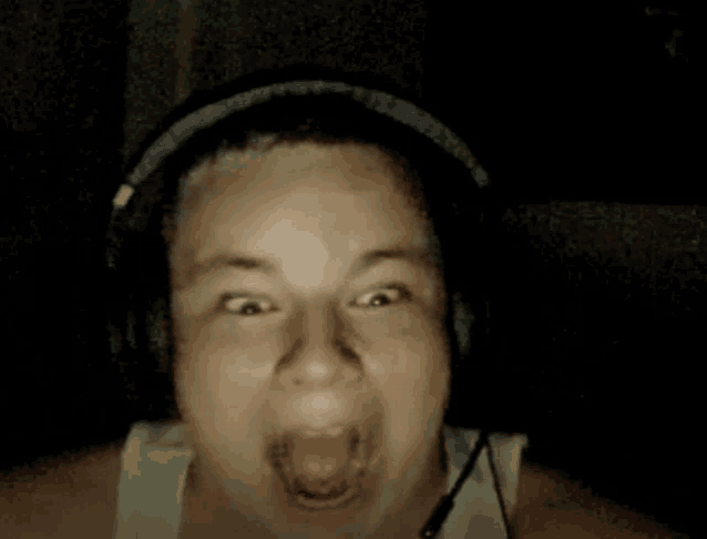 a man wearing headphones is making a funny face with his mouth open .