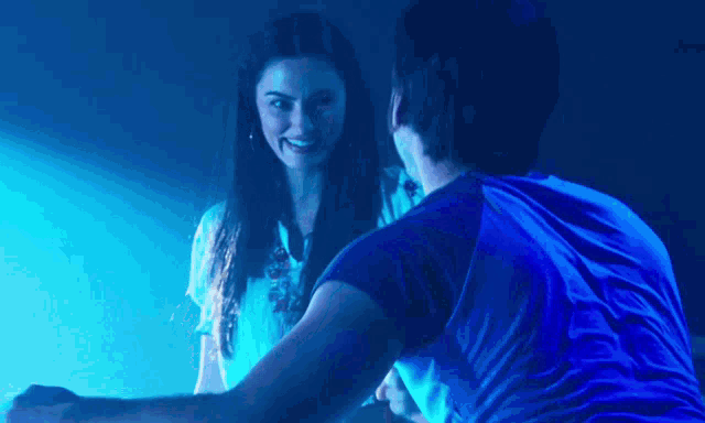 a man and woman are dancing in a dark room with blue lights behind them .