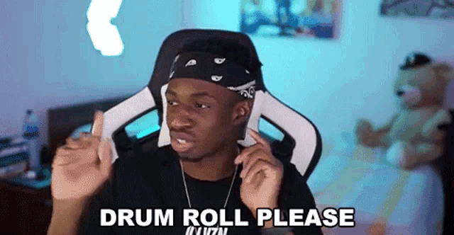 a man wearing a bandana and headphones is sitting in a chair and making a drum roll please gesture .