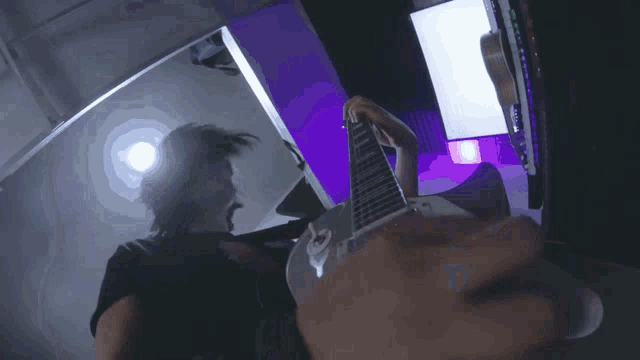 a person playing a guitar with purple lights behind them