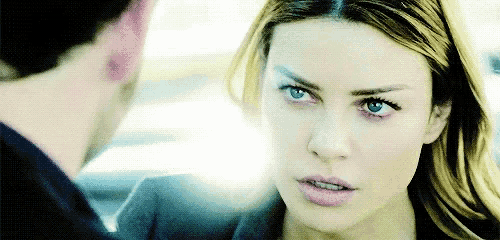 a close up of a woman 's face with a man behind her