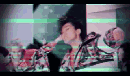 a man in a plaid jacket is standing in a room with a green and white background .