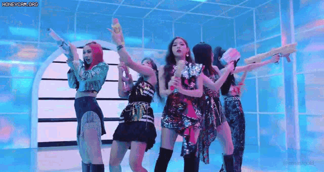 a group of girls are holding water guns in their hands while dancing on a stage .