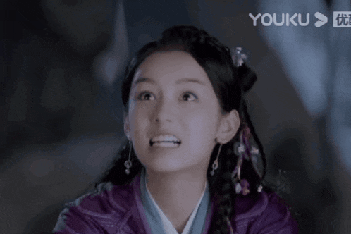 a close up of a woman 's face with a youku logo behind her