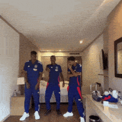 three men in blue uniforms are dancing in a room