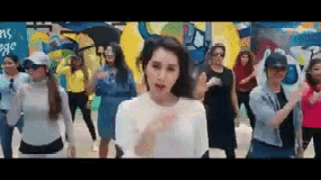 a group of women are dancing together in front of a mural .