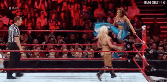 two women are wrestling in a wrestling ring with a referee watching .