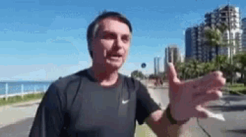a man is standing on a sidewalk with his arms outstretched and talking .