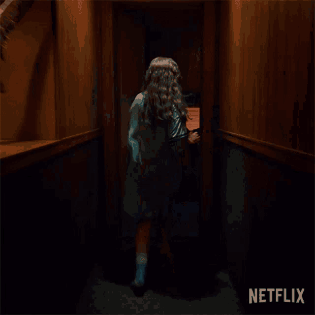 a girl in a blue dress is running down a hallway .