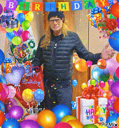 a man in a black jacket is surrounded by balloons and gifts with a happy birthday banner behind him