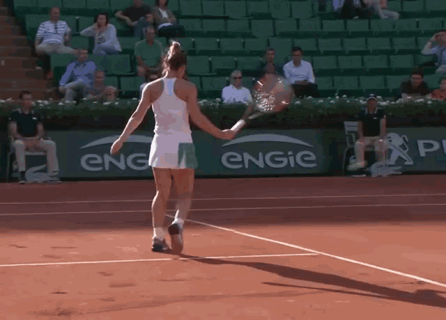 a woman is holding a tennis racquet on a tennis court in front of an engie sign