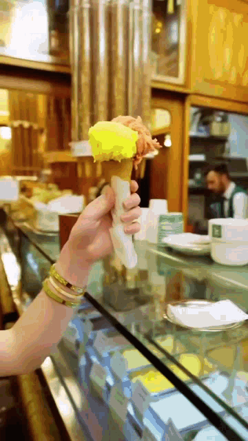 a person holding an ice cream cone with a yellow flavor