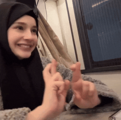a woman wearing a black hijab is smiling and giving a thumbs up