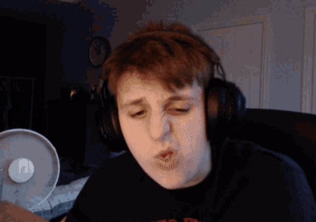 a young man wearing headphones and a shirt that says ' a ' on it is making a funny face