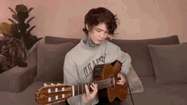 a person playing an acoustic guitar with a sweater that says dawn on it