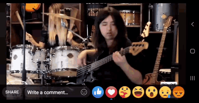 a man playing a guitar in front of a drum set with a share button