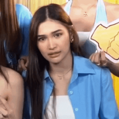 a woman in a blue shirt is standing in front of a group of girls .