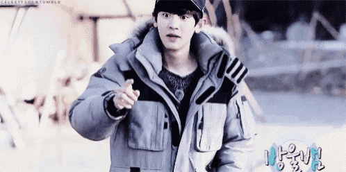 a young man in a gray jacket and black hat is pointing at something .