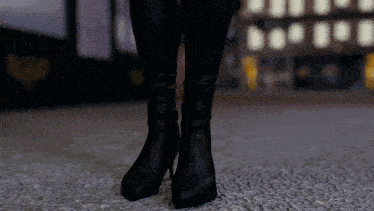 a woman wearing a pair of black boots standing on a carpet
