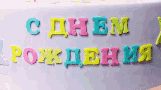a birthday cake with colorful letters and a candle