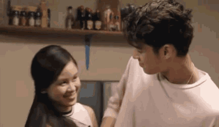 a man and a woman are standing next to each other in a kitchen and looking at each other .