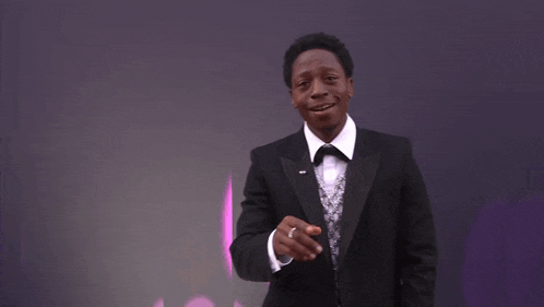 a man in a suit and tie is smiling in front of a purple background