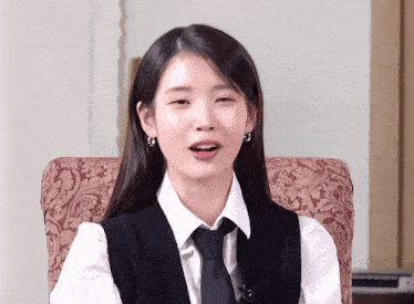a woman wearing a white shirt and black tie sitting in a chair