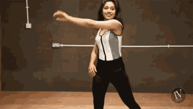 a woman is dancing in a dance studio while wearing a bodysuit and leggings .