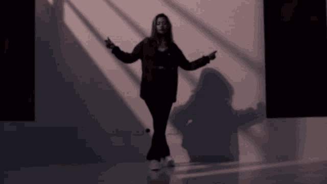a woman is standing in front of a wall with a shadow on it