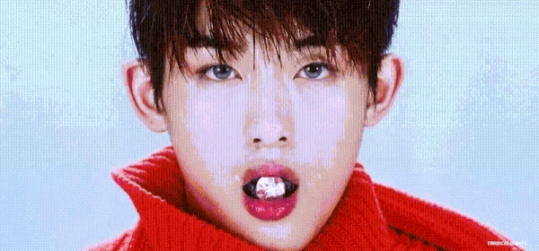 a close up of a young man wearing a red sweater and a red scarf with a candy in his mouth .