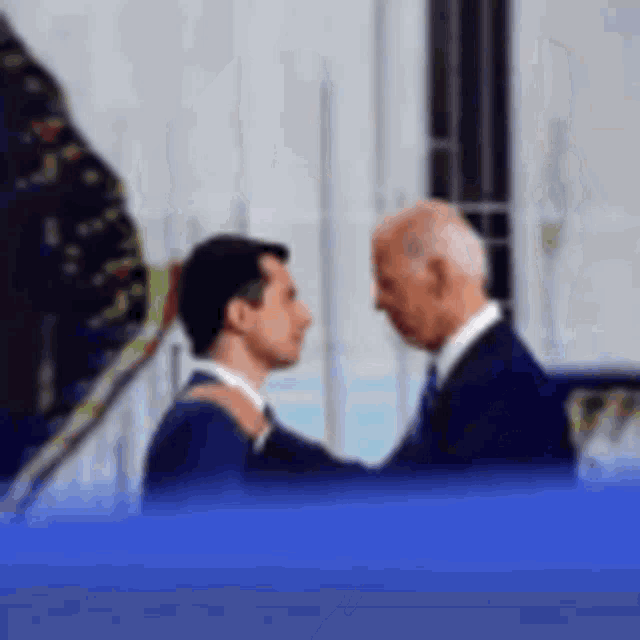 a man in a suit and tie is hugging another man in a suit .