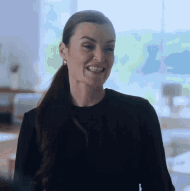 a woman in a black sweater is smiling and looking at the camera