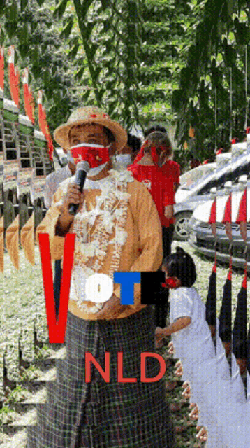 a woman wearing a mask stands in front of a microphone with the words vote nld on the bottom