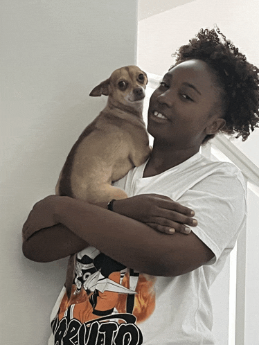a girl holding a small brown dog wearing a shirt that says naruto